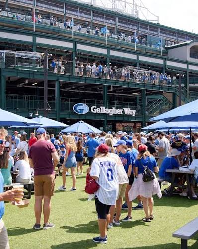 Cubs fans in jerseys packing the Gallagher Way plaza on a sunny game day outside Wrigley Field